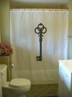 a bathroom with a shower curtain that has an old key on it and pink flowers in the background