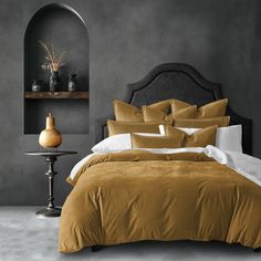 a bed with brown sheets and pillows in a room next to a lamp on a table