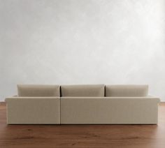 a couch sitting on top of a hard wood floor next to a white wall in an empty room