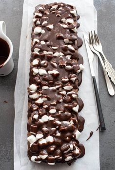 a piece of chocolate cake with marshmallows on it and a cup of coffee next to it