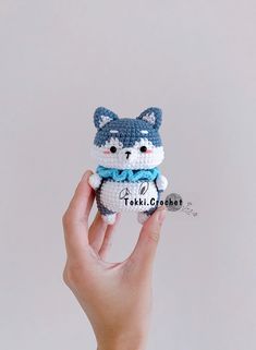 a hand holding a small crocheted cat doll in it's left hand