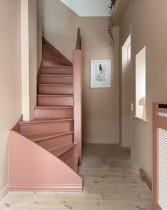 a pink staircase in a house with wood flooring and white trim on the walls