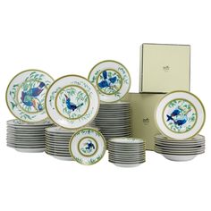 a set of twelve plates with blue and green birds on them, in front of a box