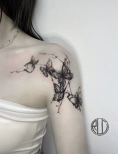 a woman's shoulder with black and white tattoos on her left arm, which is decorated with butterflies