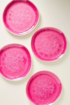 three pink plates sitting next to each other on a white counter top with water droplets all over them