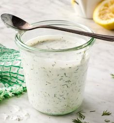 a glass jar filled with yogurt next to a spoon