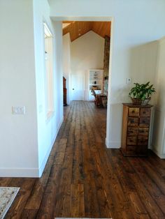 an empty living room with wood floors and white walls is seen from the hallway to the dining area