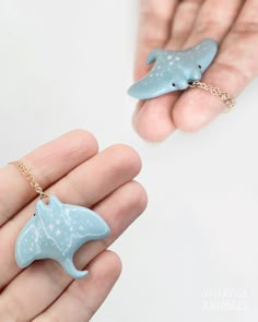 a hand holding a tiny dolphin necklace and a small dolphin keychain in it's palm