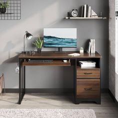 a desk with a computer on it in front of a gray wall and white rug