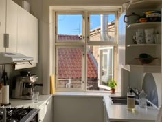 a kitchen with a stove top oven sitting next to a window filled with pots and pans