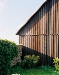 the side of a building that is made out of wood and has grass growing around it