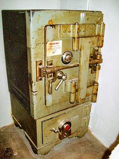 an old fashioned stove sitting in a corner next to a white wall and carpeted floor