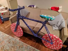 a bicycle made out of fabric sitting on top of a wooden floor next to a couch