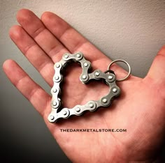 a hand holding a heart shaped bike chain keychain in it's palm