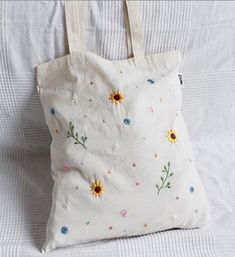 a white tote bag with sunflowers and daisies embroidered on the front