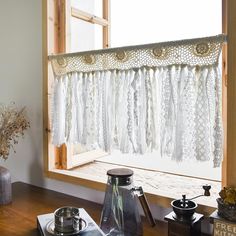 a window with lace curtains hanging from it's side and other items on the windowsill