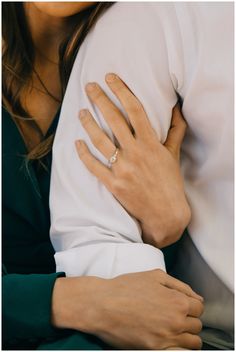 a close up of a person's hand holding another persons arm with their engagement ring