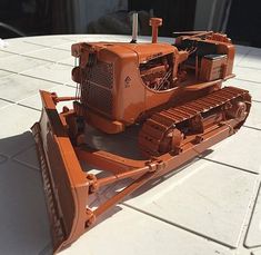 an orange toy bulldozer sitting on top of a white tile floor next to a building