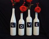 three wine bottles with flowers in them sitting next to each other on a black background