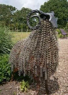 a sculpture of a cow made out of metal wires and other items in a garden