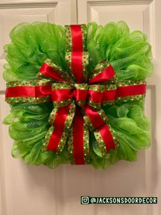 a green wreath with red bow hanging on a door