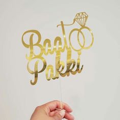 a hand holding a cake topper that says baket pakki on it