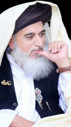 a man with a long white beard wearing a turban and holding his finger to his chin