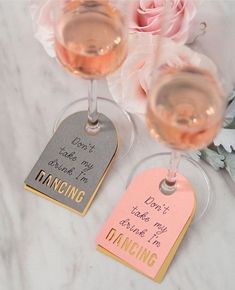 two wine glasses sitting next to each other on top of a marble table with pink flowers