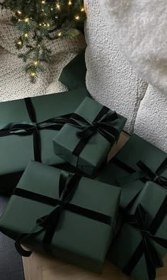 a pile of green wrapped presents next to a christmas tree