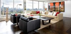 a living room filled with furniture and large windows overlooking the cityscape in the distance