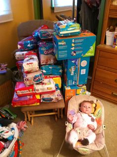 a baby is sitting in a chair next to many diapers and boxes on the floor