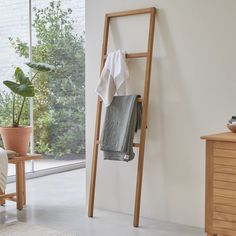 a towel rack in the corner of a room with a chair and potted plant