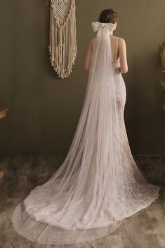 a woman in a wedding dress looking down at her veil