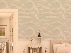 a child's bedroom decorated in pink and white with clouds painted on the wall