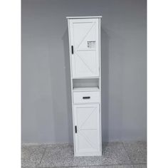 a tall white cabinet with doors and drawers on the bottom shelf, against a gray wall