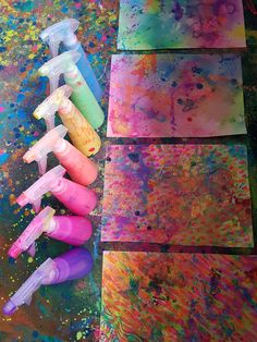 four different colors of paint sitting next to each other on top of a table covered in paper