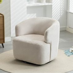 a white chair sitting on top of a rug in a living room next to a dresser