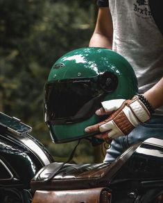 a person wearing a green helmet and gloves sitting on a motorcycle