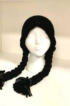 a white mannequin head wearing a black knitted hat with tassels