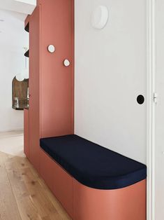 an orange and blue bench sitting in the middle of a room next to a white wall