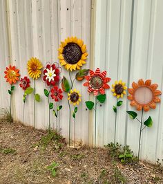 sunflowers and other flowers are painted on the side of a white fence with green leaves