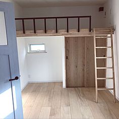 an empty room with wooden floors and ladder to the top floor, next to a window