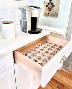 an open drawer in a kitchen filled with magnets and coffee maker on the counter