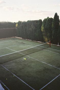 an aerial view of a tennis court with trees in the background and two people playing tennis