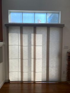 an empty room with wooden flooring and blinds on the window sill, in front of a brick fireplace