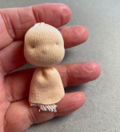 a hand holding a tiny doll in it's palm