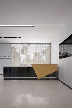 an office lobby with white walls and black counter tops, along with a yellow triangular shaped sign on the wall