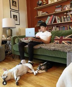 a man sitting on a couch with his dog and laptop