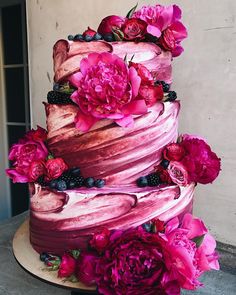 a multi layer cake with flowers and berries on top