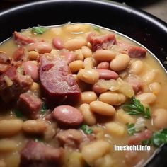 a black bowl filled with beans and ham